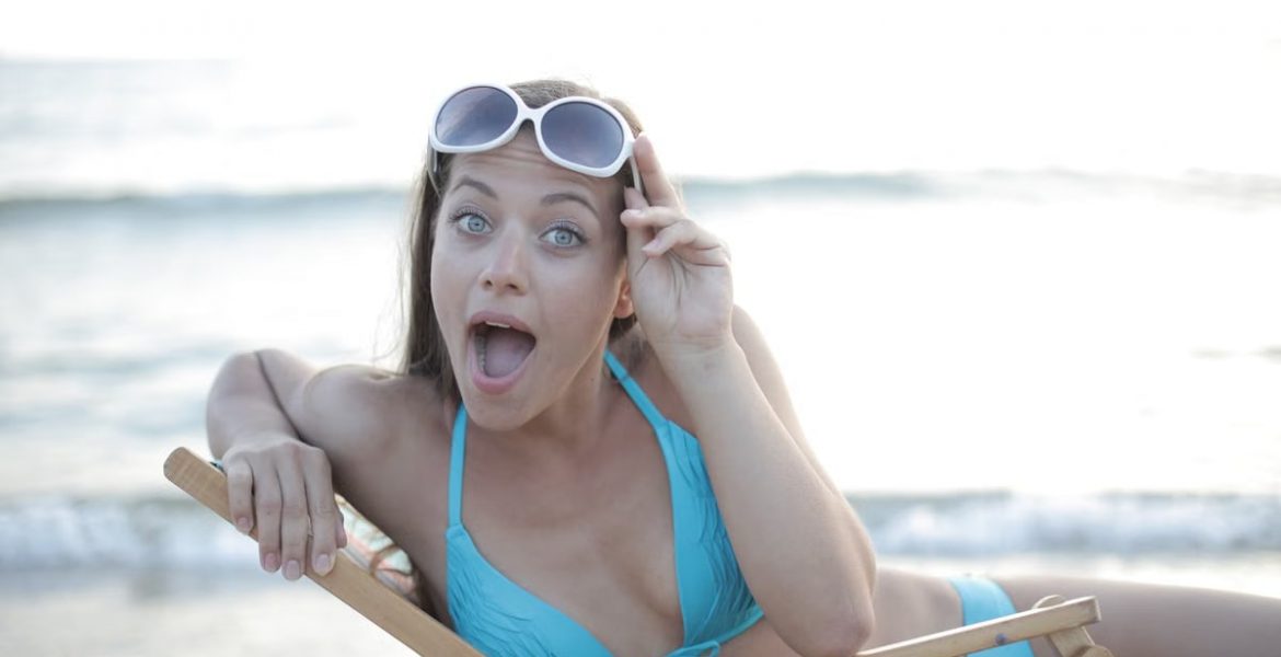 Woman in a bikini reclining on a beach chair, making a playful face.