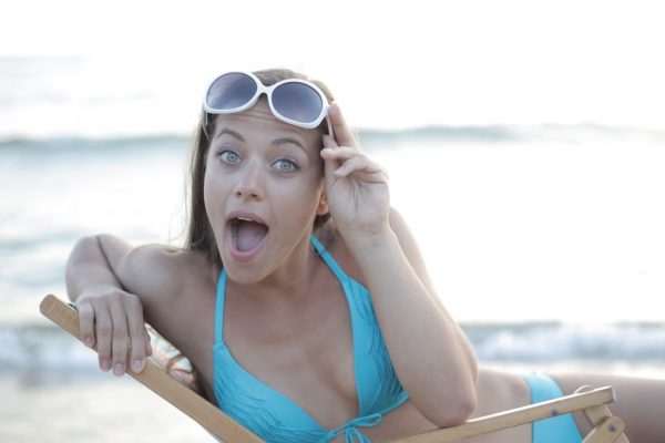 Woman in a bikini reclining on a beach chair, making a playful face.