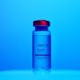 Vial of COVID-19 vaccine labeled for injection, set against a blue background.