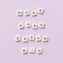 Scrabble tiles spell 'Work Hard Dream Big' on a pastel purple surface, top view.